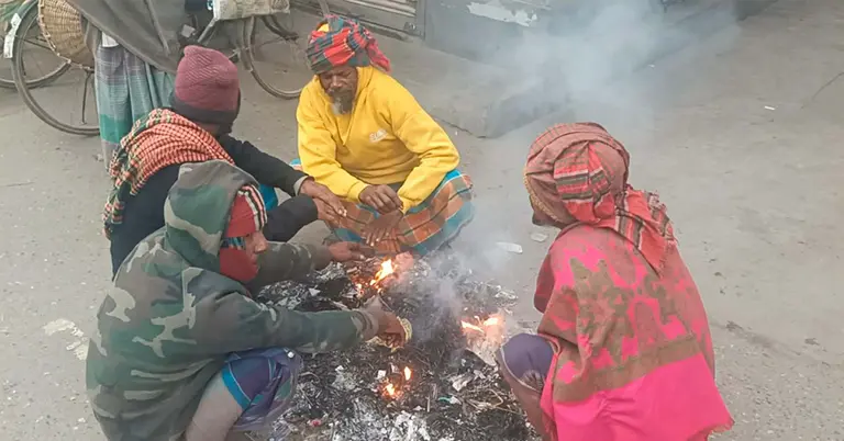 শীতে আগুন জ্বালিয়ে নিজেদের উষ্ণ রাখার চেষ্টা করছেন গ্রামের কয়েকজন মানুষ